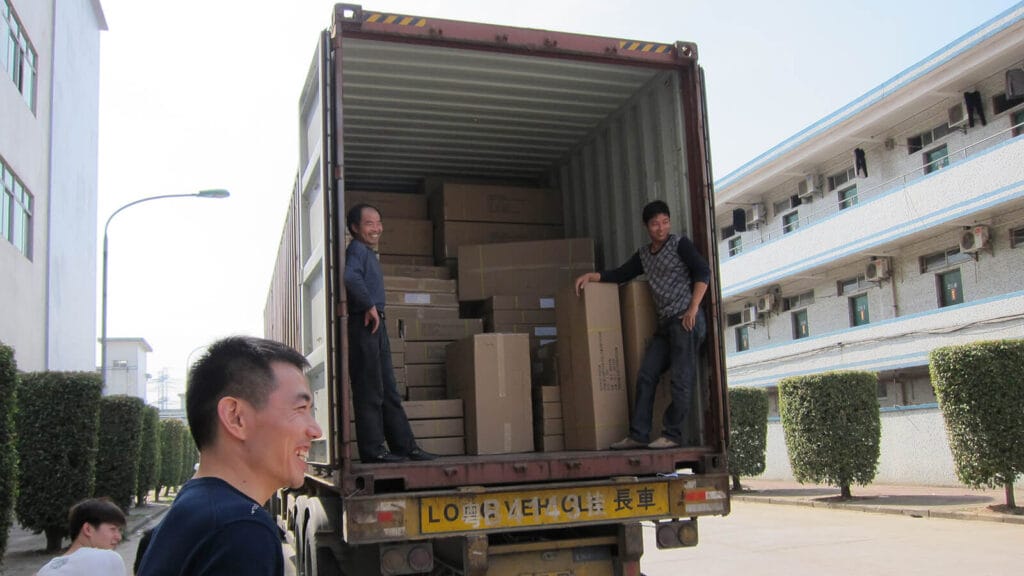 Factory workers happily loading boxed acrylic lectern orders into export container at Acrylic2GO Shenzhen factory