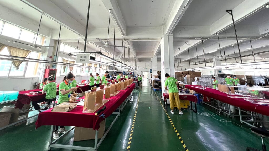 Acrylic lectern factory production floor with workers assembling orders, Shenzhen China