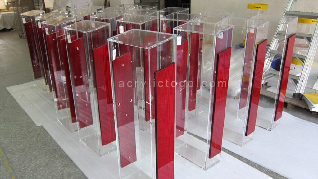 Bulk production of clear acrylic lecterns with red lacquered wood center panels, factory floor ready for export