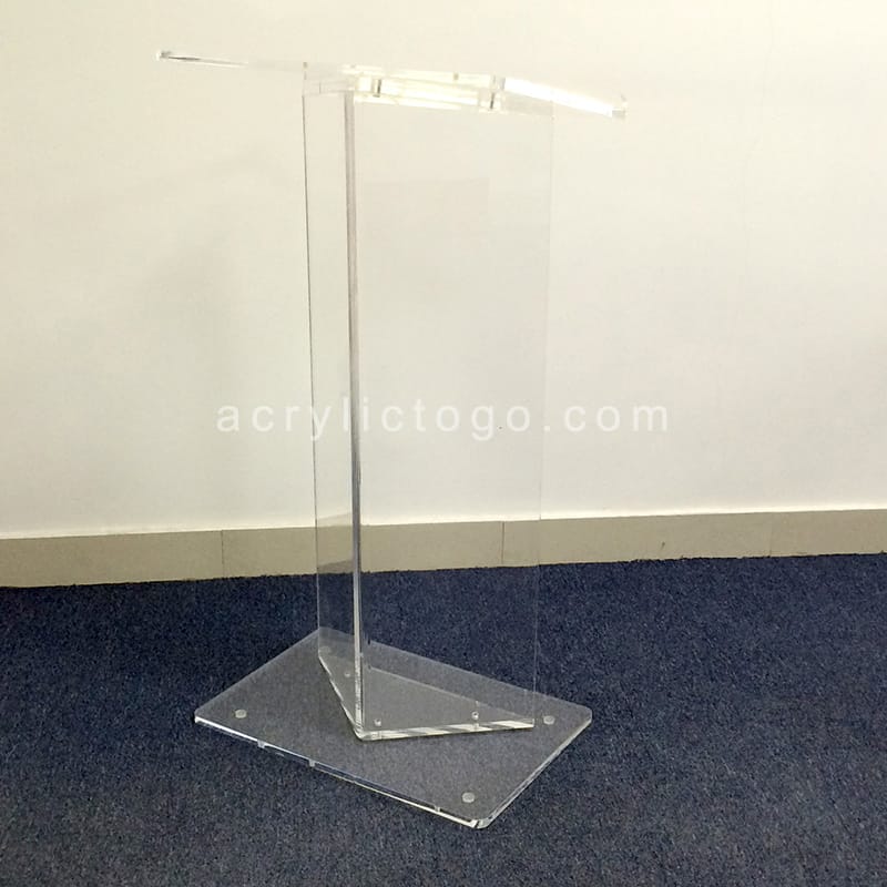 Clear acrylic T-shape minimalist lectern with wide rectangular base on blue carpet