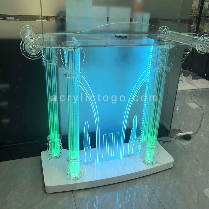 Clear acrylic LED lectern with illuminated columns and green blue RGB lighting in showroom
