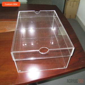 Clear acrylic shoe box on wooden table under bright light — semicircle finger-notch handle on lid visible, high-transparency PMMA sneaker storage box