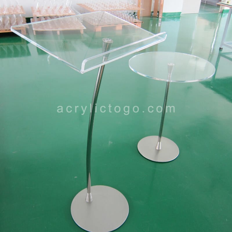Clear acrylic slanted podium and round table on stainless steel curved stands, factory floor