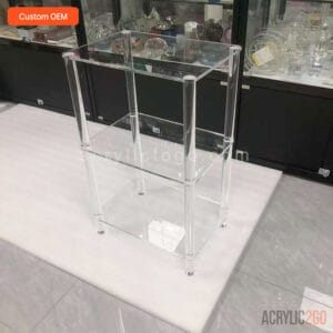 Three-tier acrylic bookshelf with cylindrical acrylic legs and mirrored reflective finish