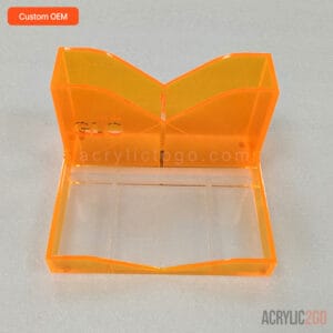 Neon orange acrylic desk organizer with a wave-shaped back panel and three-section compartment tray, front view