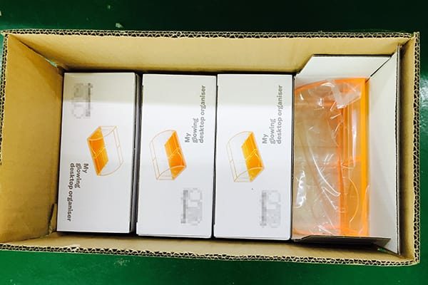 Open shipping carton showing custom white product boxes and acrylic pieces wrapped in protective PP bags